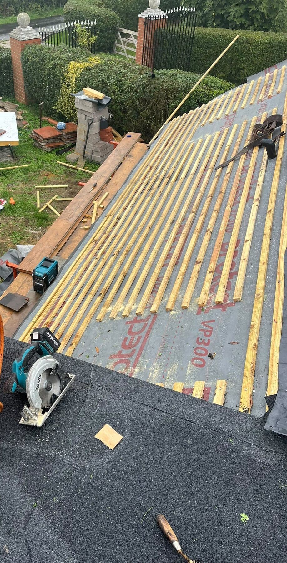 A felt flat roof beside a pitched roof that has new membrane and battens