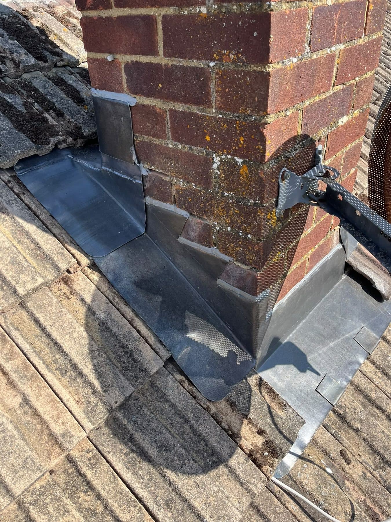 A new lead apron and step flashing around the base of a brick chimney