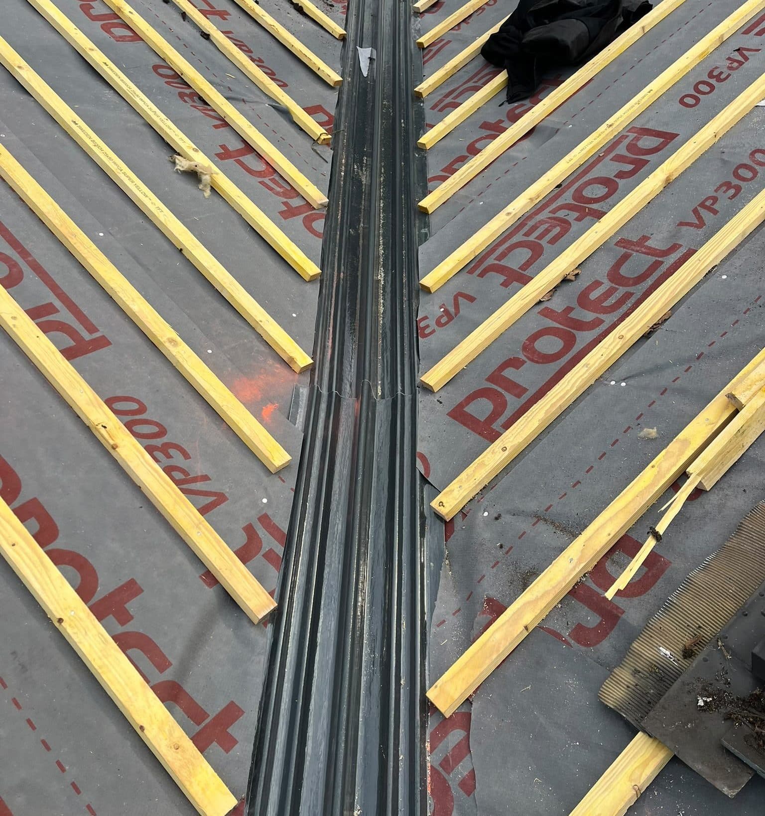 A new valley trough running down between two slopes of new membrane and battens