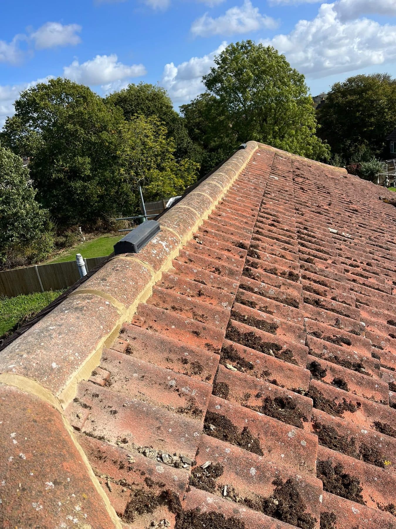 Ridge tiles on fresh mortar along the top of a clay tiled roof