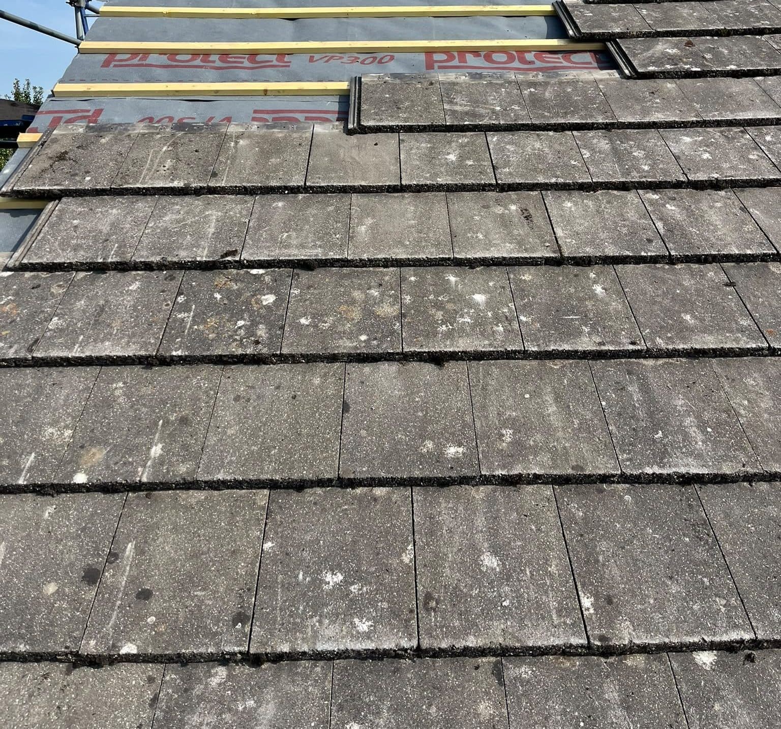 Weathered plain tiles laid course by course over new membrane and battens