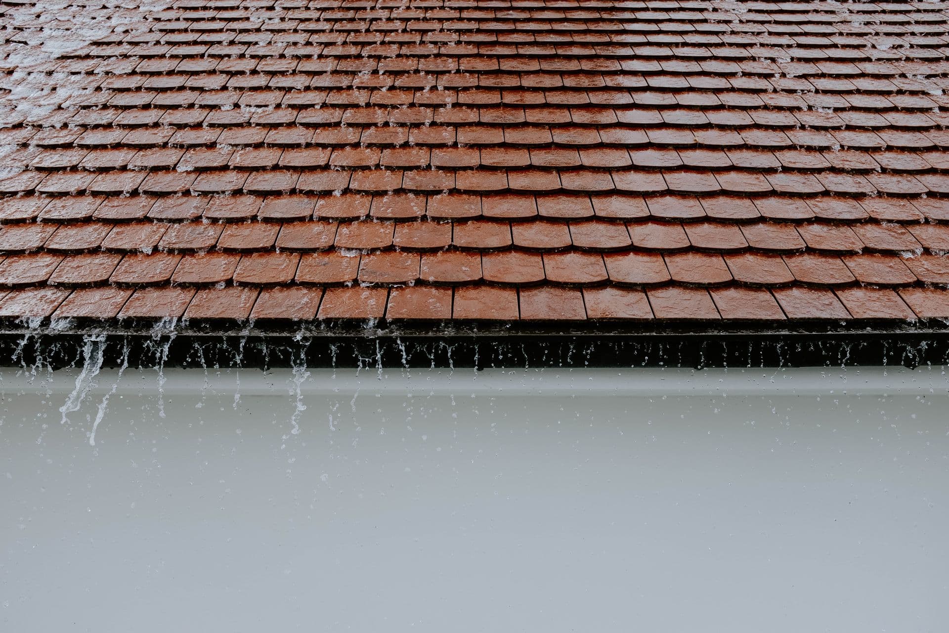Rain running off a tiled roof into the gutter along the eaves